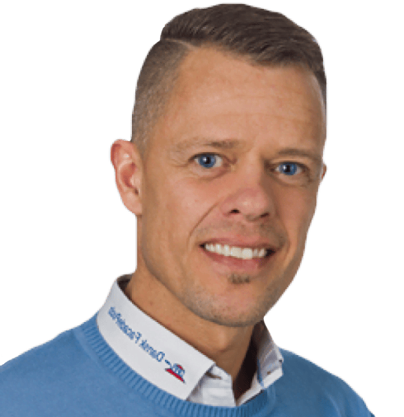 Mand smilende iført blå sweater og hvid skjorte