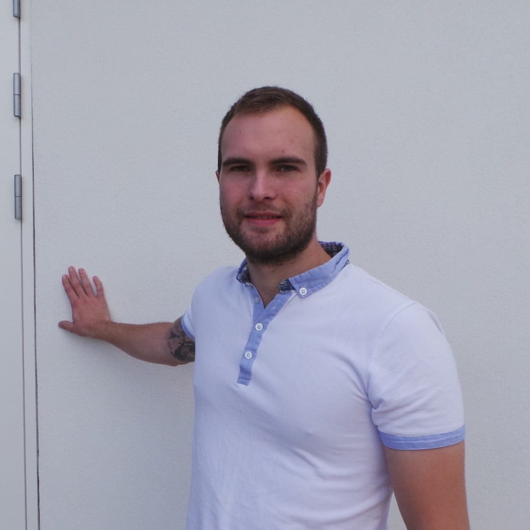 Mand står ved hvid væg og smiler