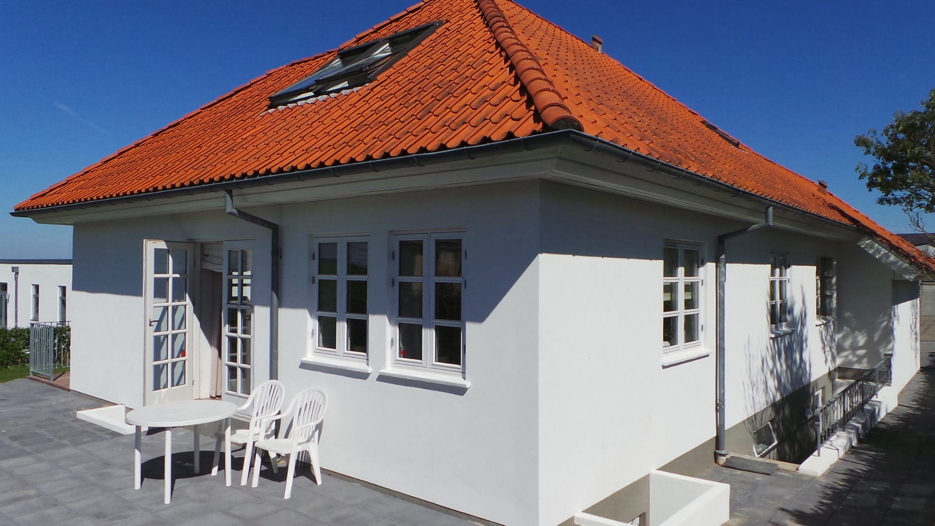 Hvidt hus med rødt tegltag og terrasse