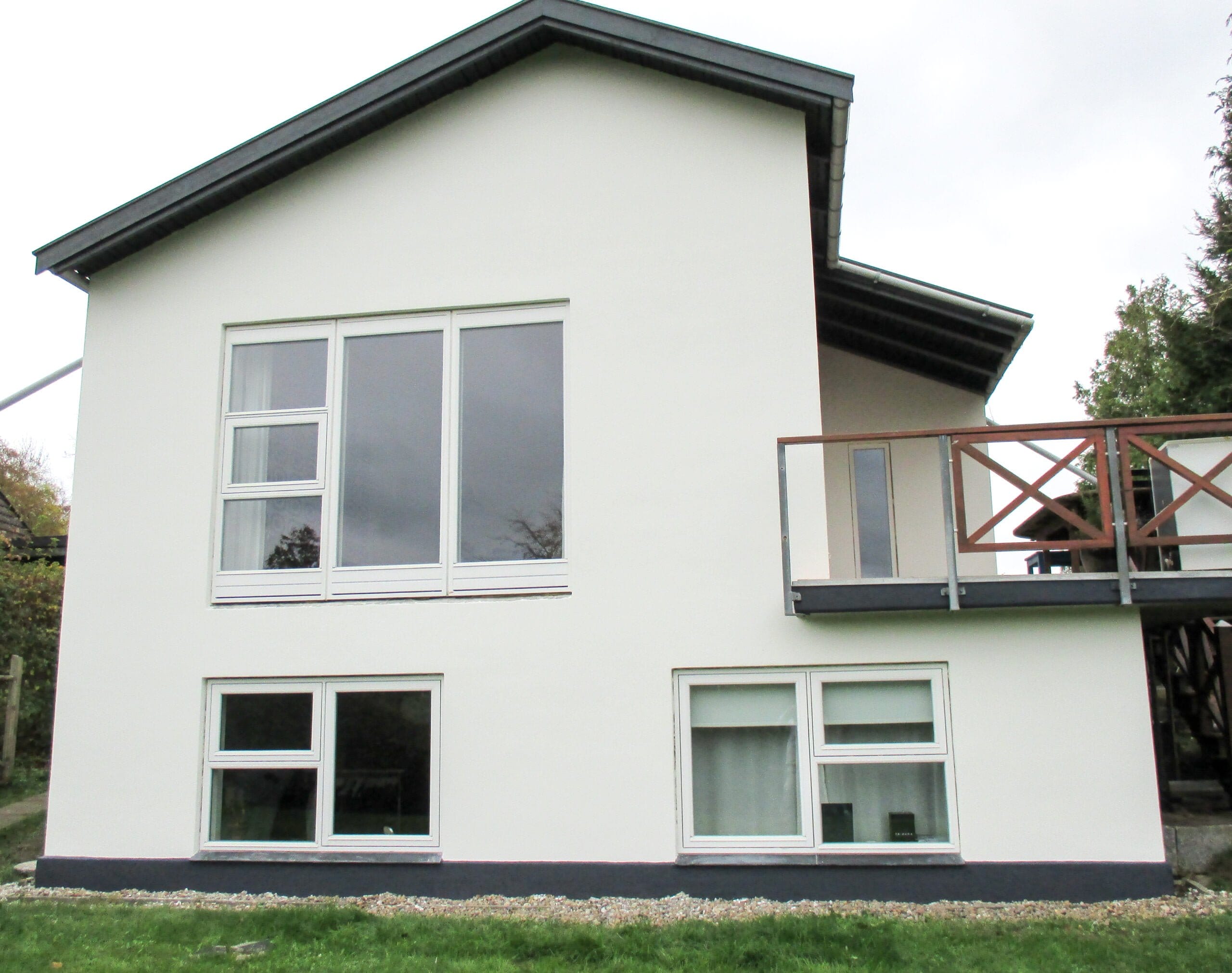 Moderne hvid facade på to-etagers hus med altan