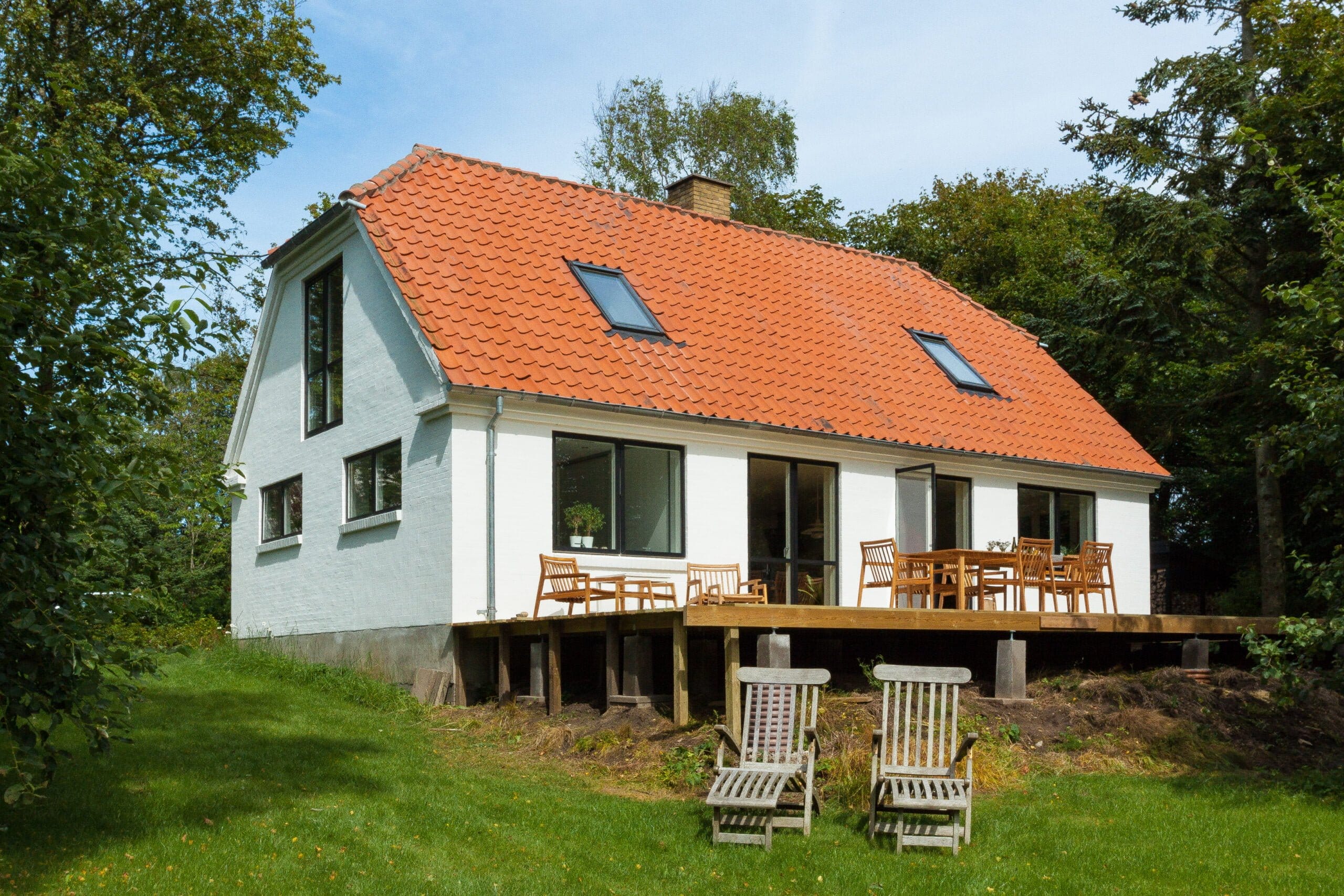 Hvidt hus med rødt tag og træterrasse