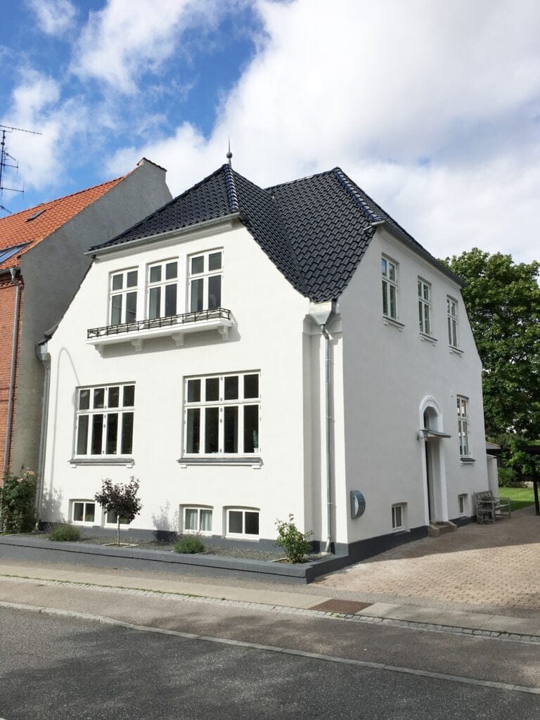 Hvid villa med sort tag i boligområde