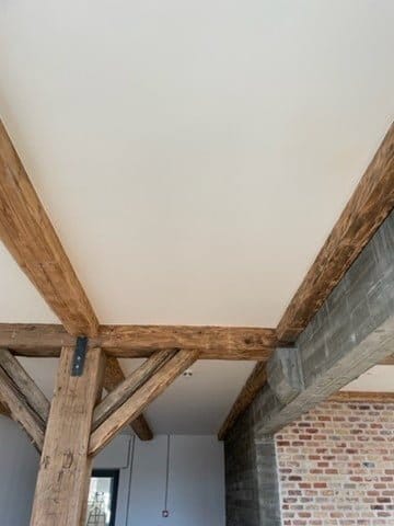 Synligt loft med træbjælker og murstensvæg