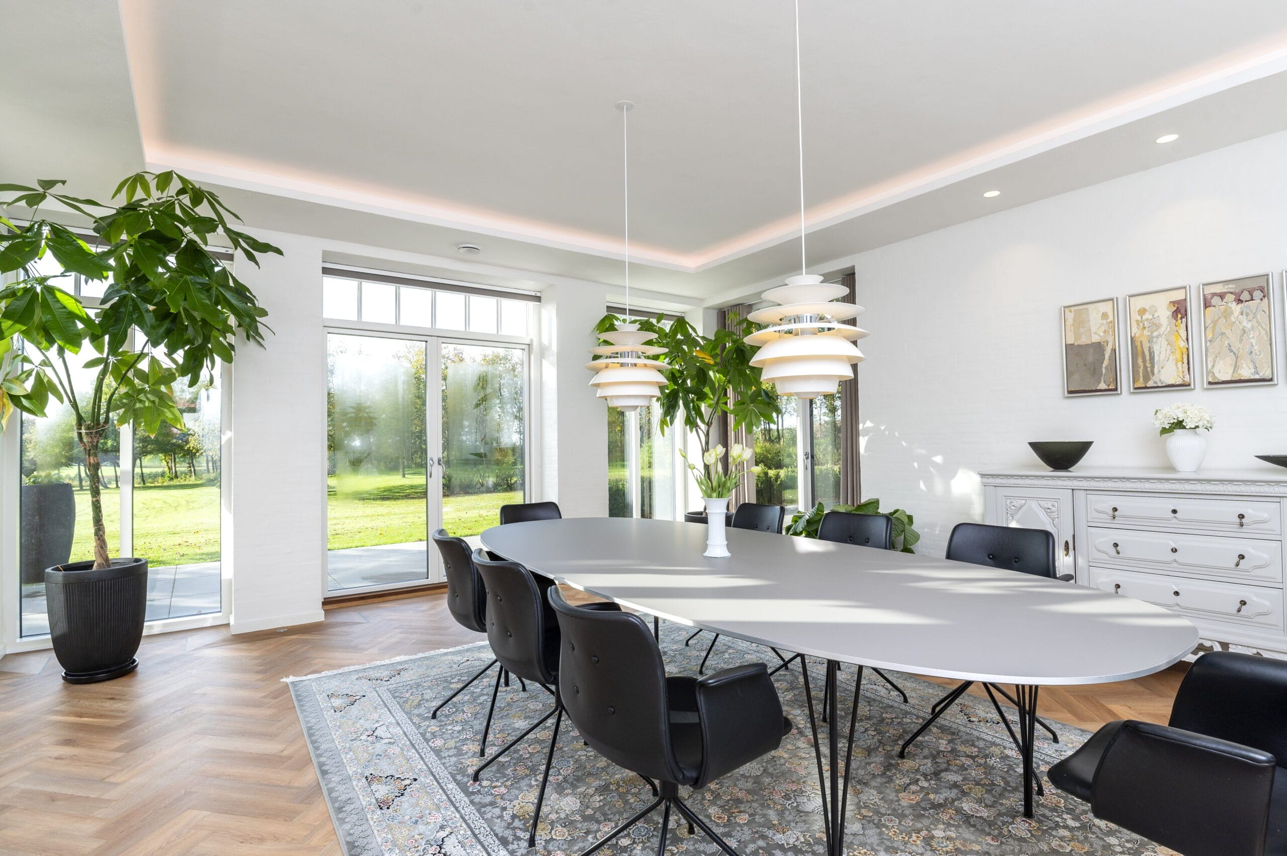 Moderne spisestue med store vinduer og grøn udsigt