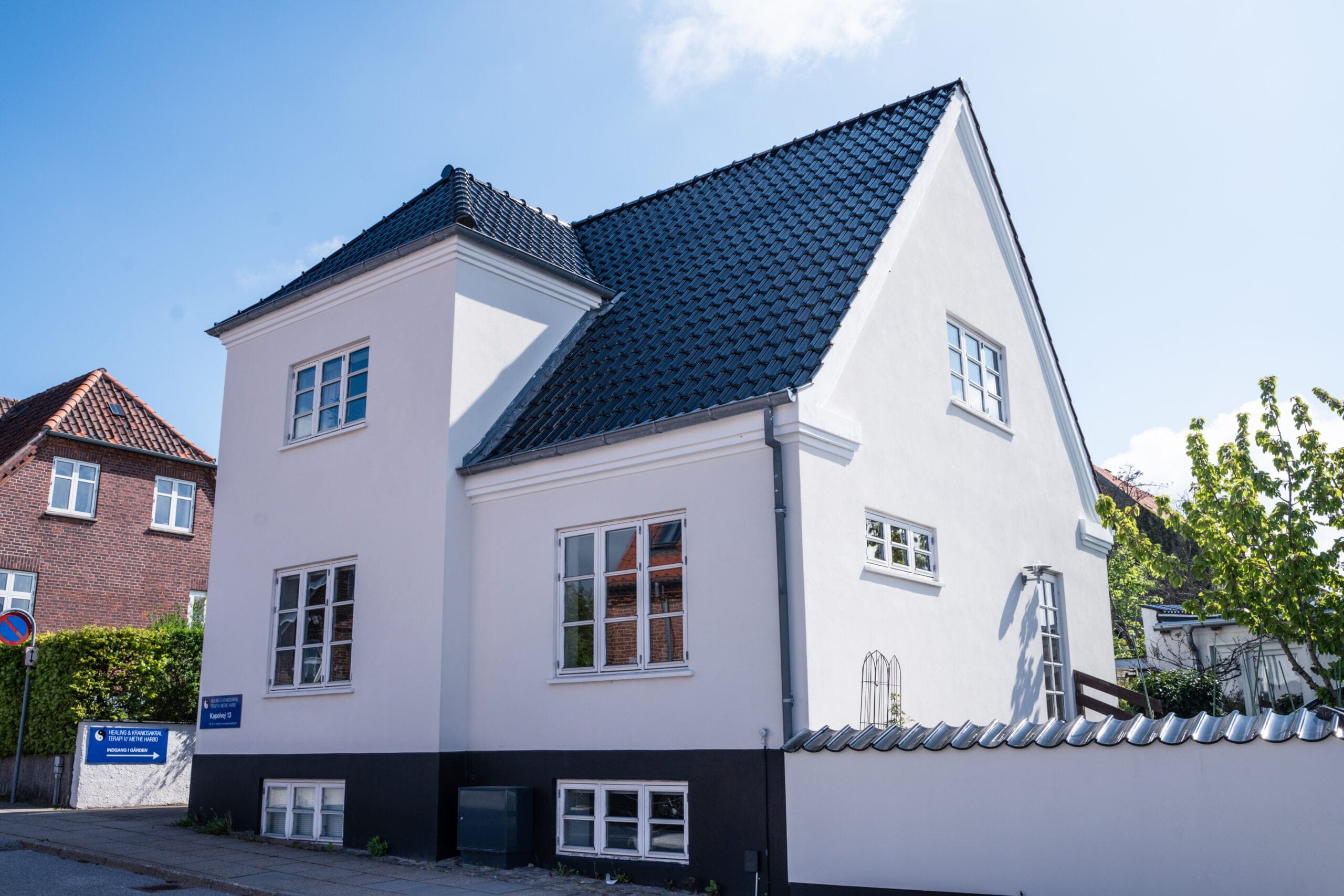 Hvidt hus med sort tag i solskin