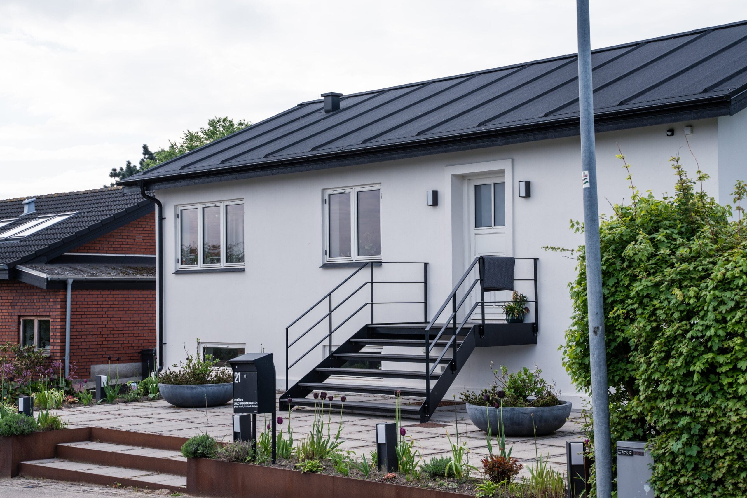 Moderne hvidt hus med sort tag og have